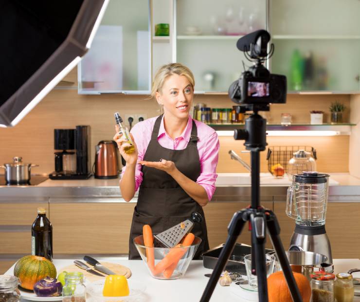 A cooking content creator standing in a kitchen in front of a camera.